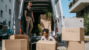 A couple loads moving boxes into a moving van