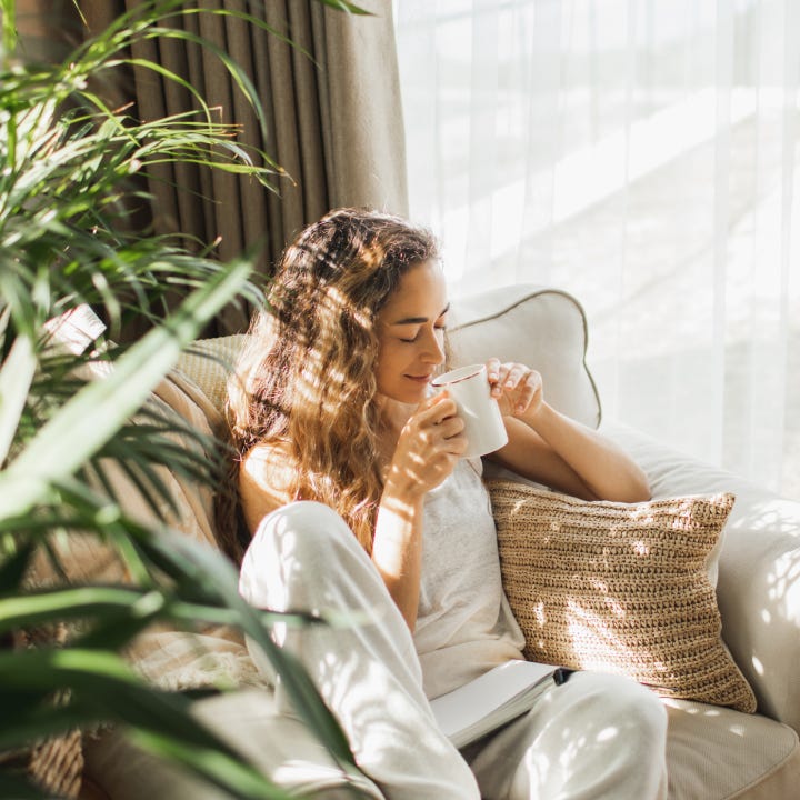Woman at home reading book and drinking coffee