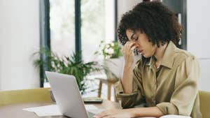 Young woman sits a computer with her head in her hand.