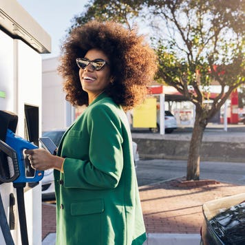 Happy businesswoman with fuel pump at gas station