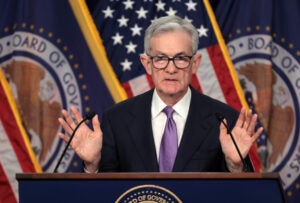 Photo of Fed Chair Jerome Powell at a podium, holding his hands up.
