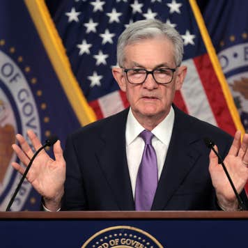 Photo of Fed Chair Jerome Powell at a podium, holding his hands up.