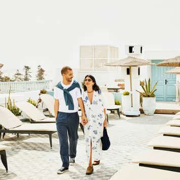 Wide shot couple walking on rooftop deck of luxury tropical resort