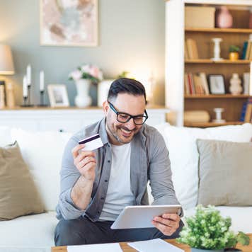 Smiling man holds tablet and credit card.