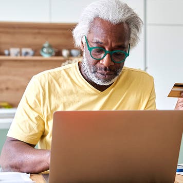 Senior man using laptop and credit card