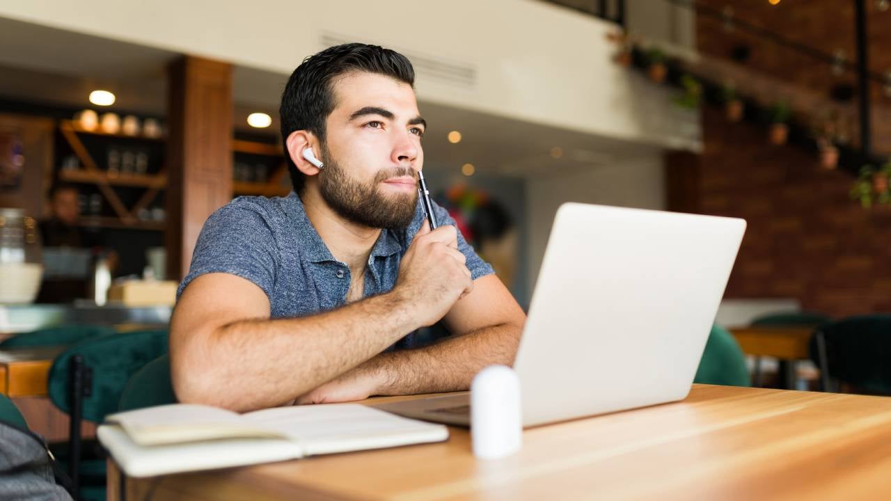 freelance worker in the cafe thinking about a new idea while doing remote work using his laptop