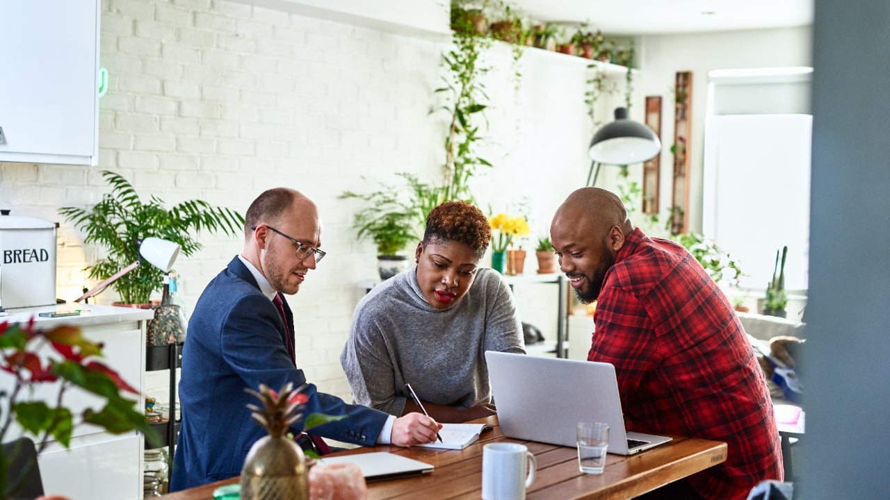 A couple speaks with a financial advisor in their kitchen