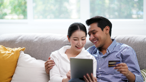 Portrait of Young Asian Couple relaxing in living room using tablet shopping online simple lifestyle in modern family