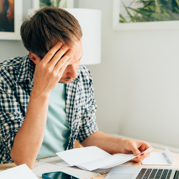 A man looks pensively at a bill he received